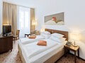 Standard Room bedroom with bed, armchair and TV | Hotel Rathauspark in Vienna